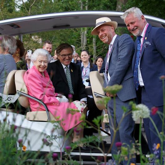Queen Elizabeth smiles with garden designer Joe Swift (2R) and Mark Gregoy (R) as she tours the garden in a buggy with RHS president, Keith Weed (2L).