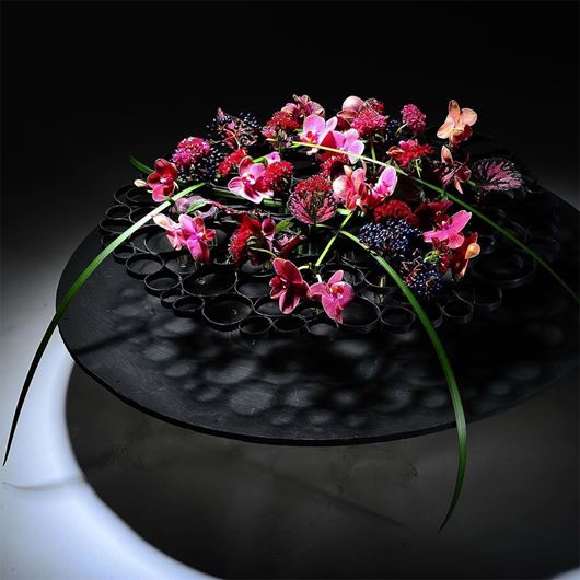 Floating black rattan ring structure with decorative floral carpet.